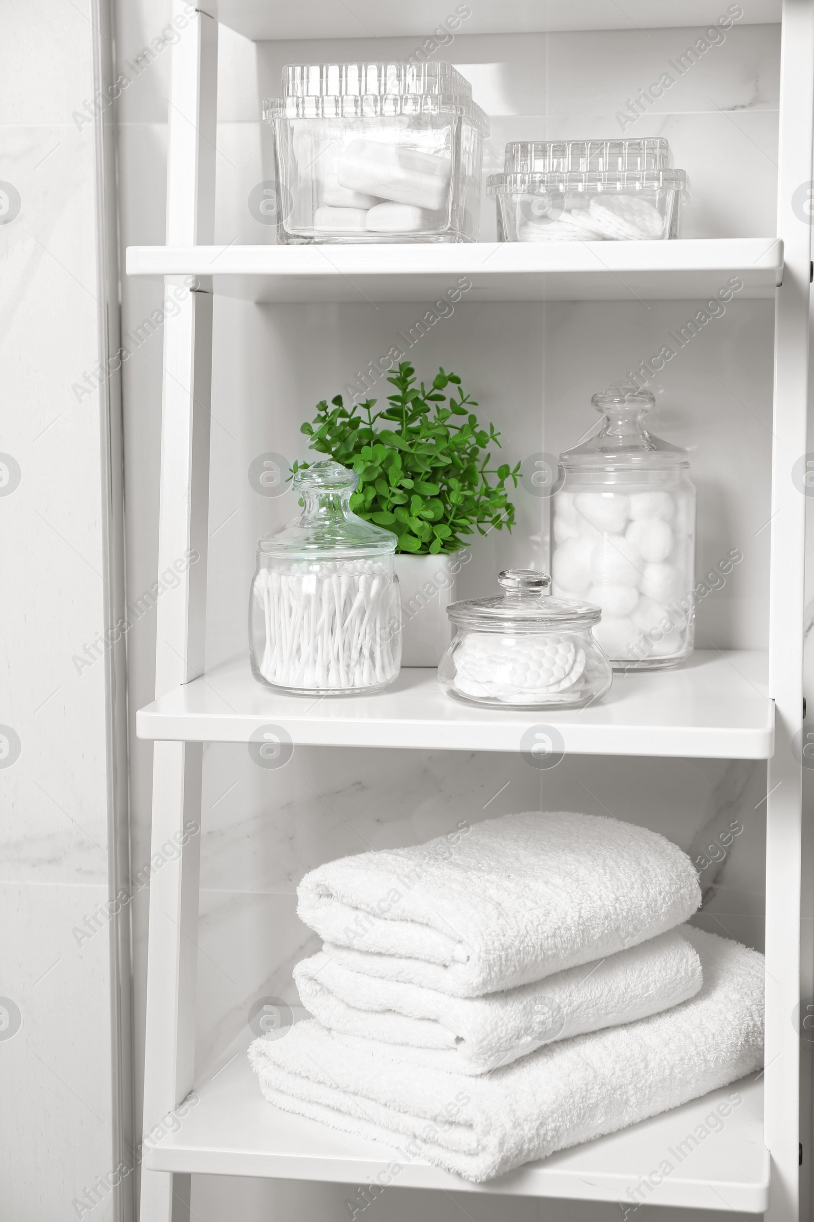 Photo of Cotton swabs and other hygiene products on shelving unit in bathroom