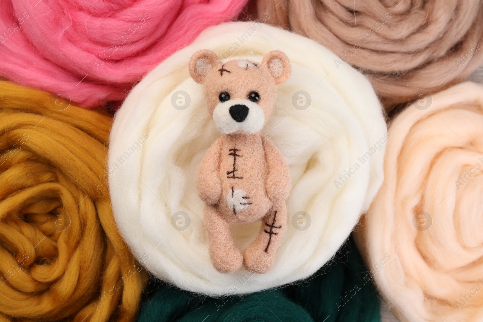 Photo of Felted bear on colorful wool, top view