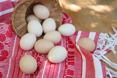 Overturned wicker basket with fresh raw eggs on table