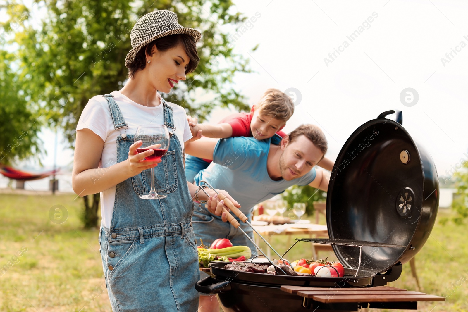 Photo of Happy family having barbecue with modern grill outdoors