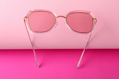 Stylish sunglasses on pink background. Summer accessory