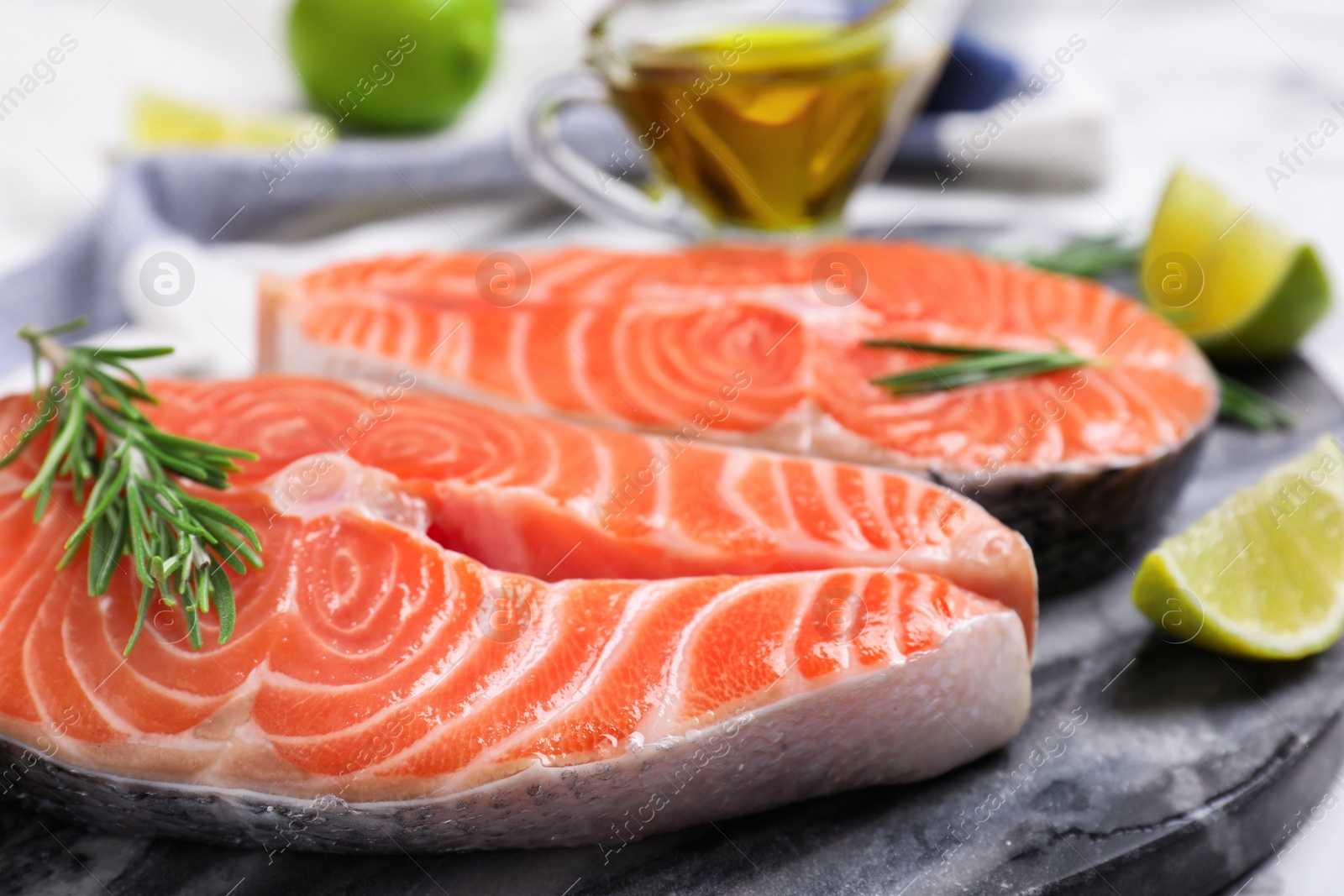 Photo of Fresh raw salmon with rosemary and lime on stone board. Fish delicacy