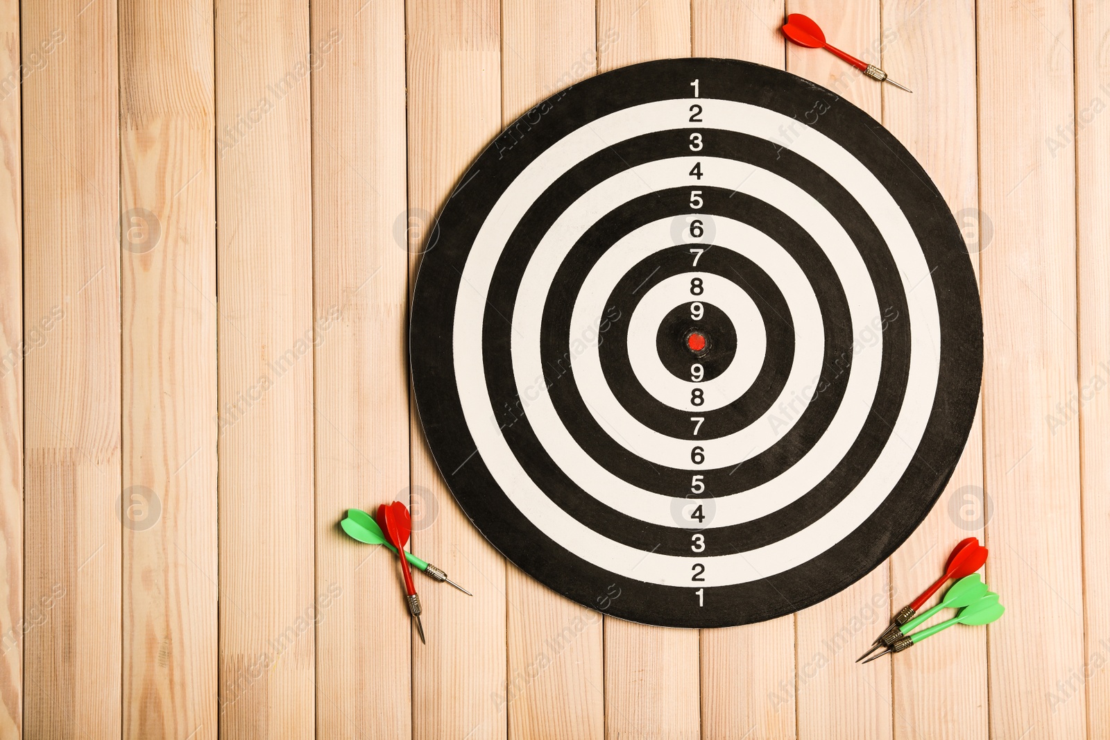 Photo of Dart board with color arrows on wooden background, top view. Space for text