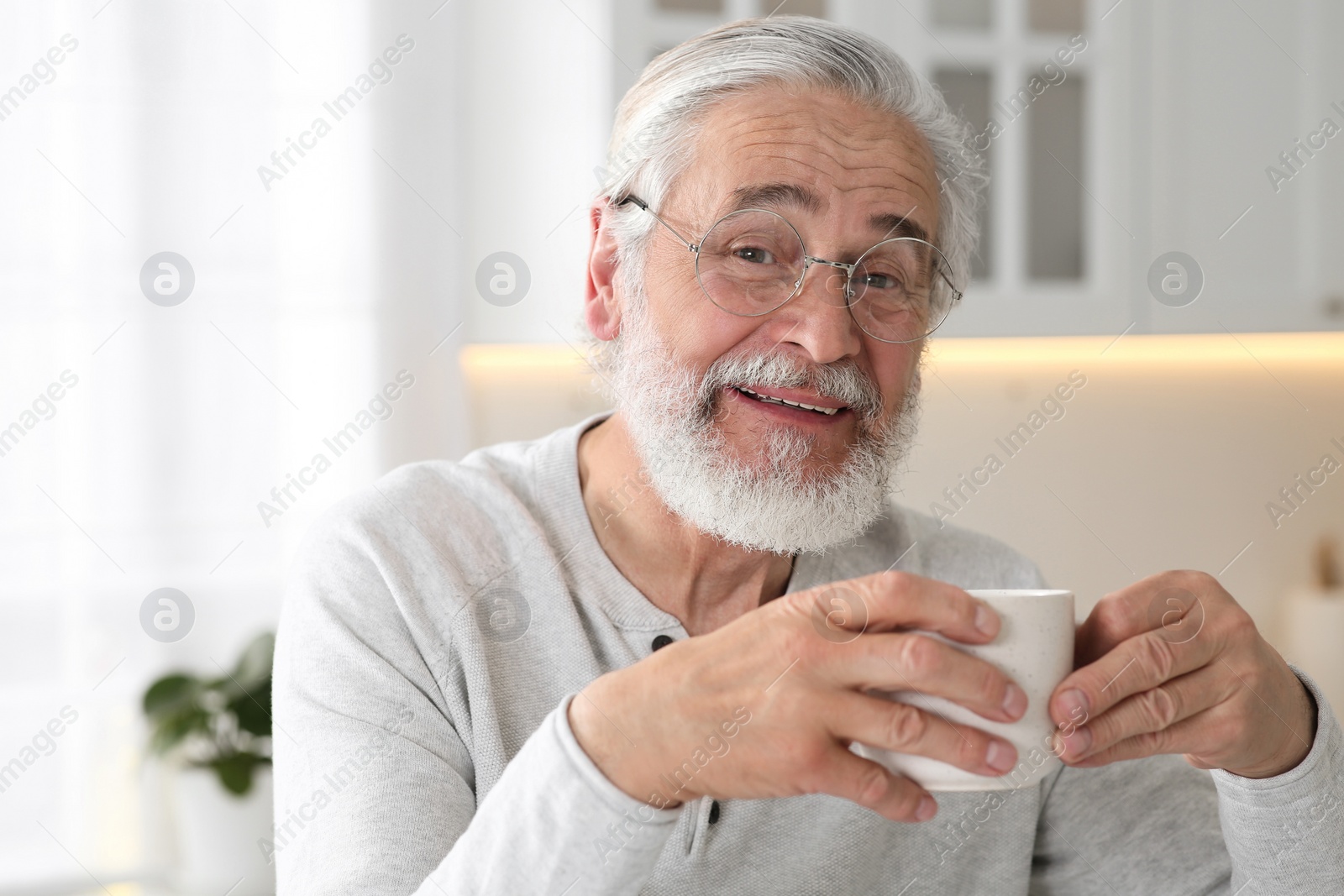 Photo of Senior man with cup of drink in kitchen