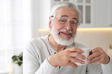 Photo of Senior man with cup of drink in kitchen