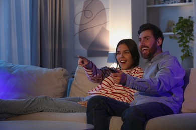 Photo of Happy couple watching TV on sofa at home, space for text