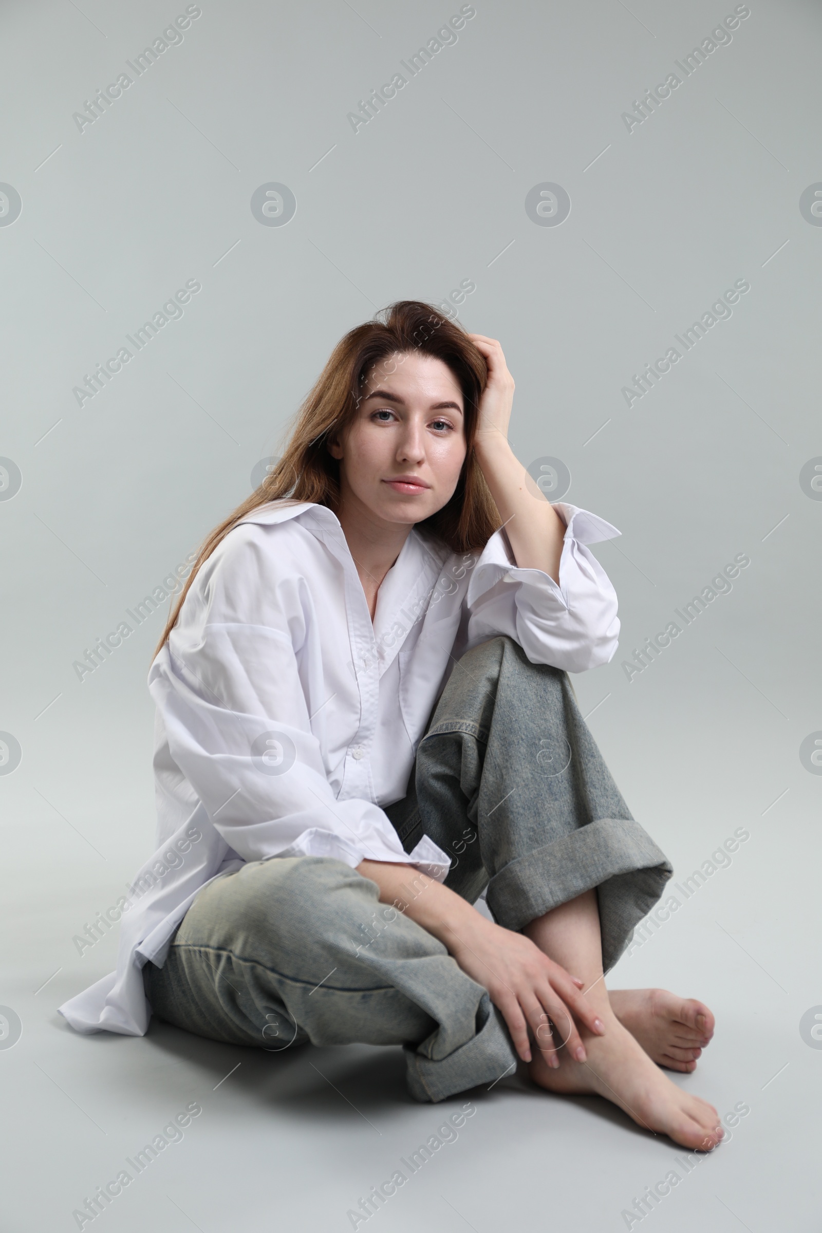 Photo of Portrait of beautiful young woman sitting on grey background