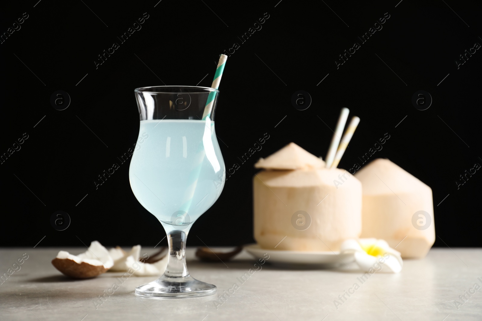 Photo of Glass with fresh coconut water on table against black background