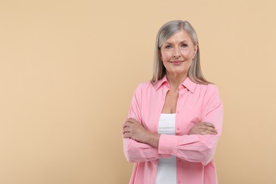 Portrait of beautiful senior woman on beige background. Space for text