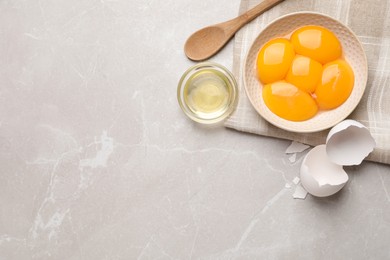 Photo of Flat lay composition with raw egg yolks and whites on light grey marble table, space for text