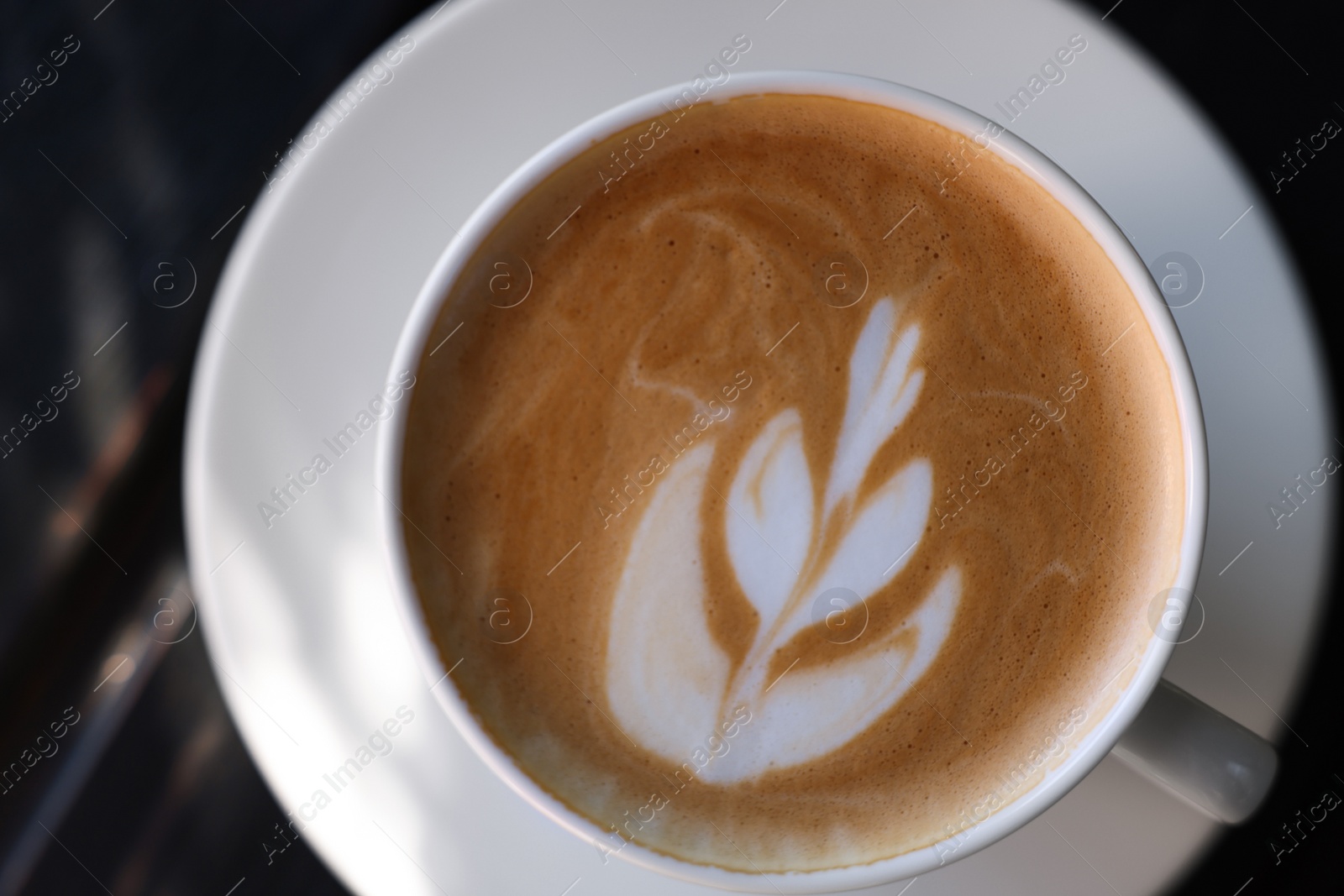 Photo of Cup of aromatic coffee with foam on wooden table, top view