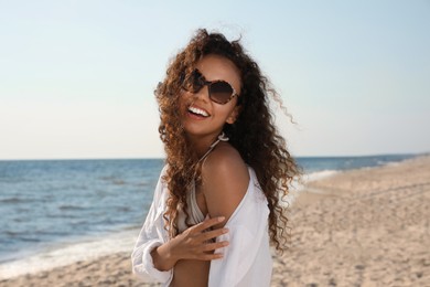 Photo of Beautiful African American woman with sunglasses at beach. Sun protection care