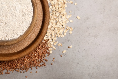 Photo of Composition with oat and buckwheat flour on grey background, top view. Space for text