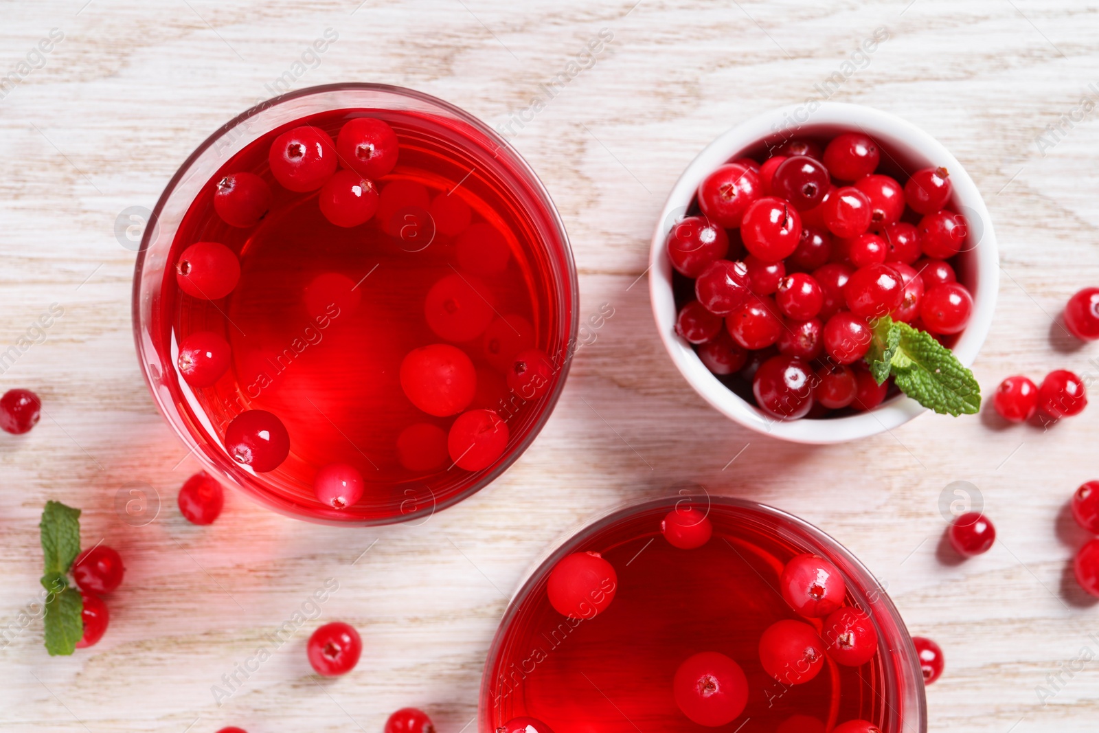 Photo of Tasty cranberry juice in glasses and fresh berries on white wooden table, flat lay