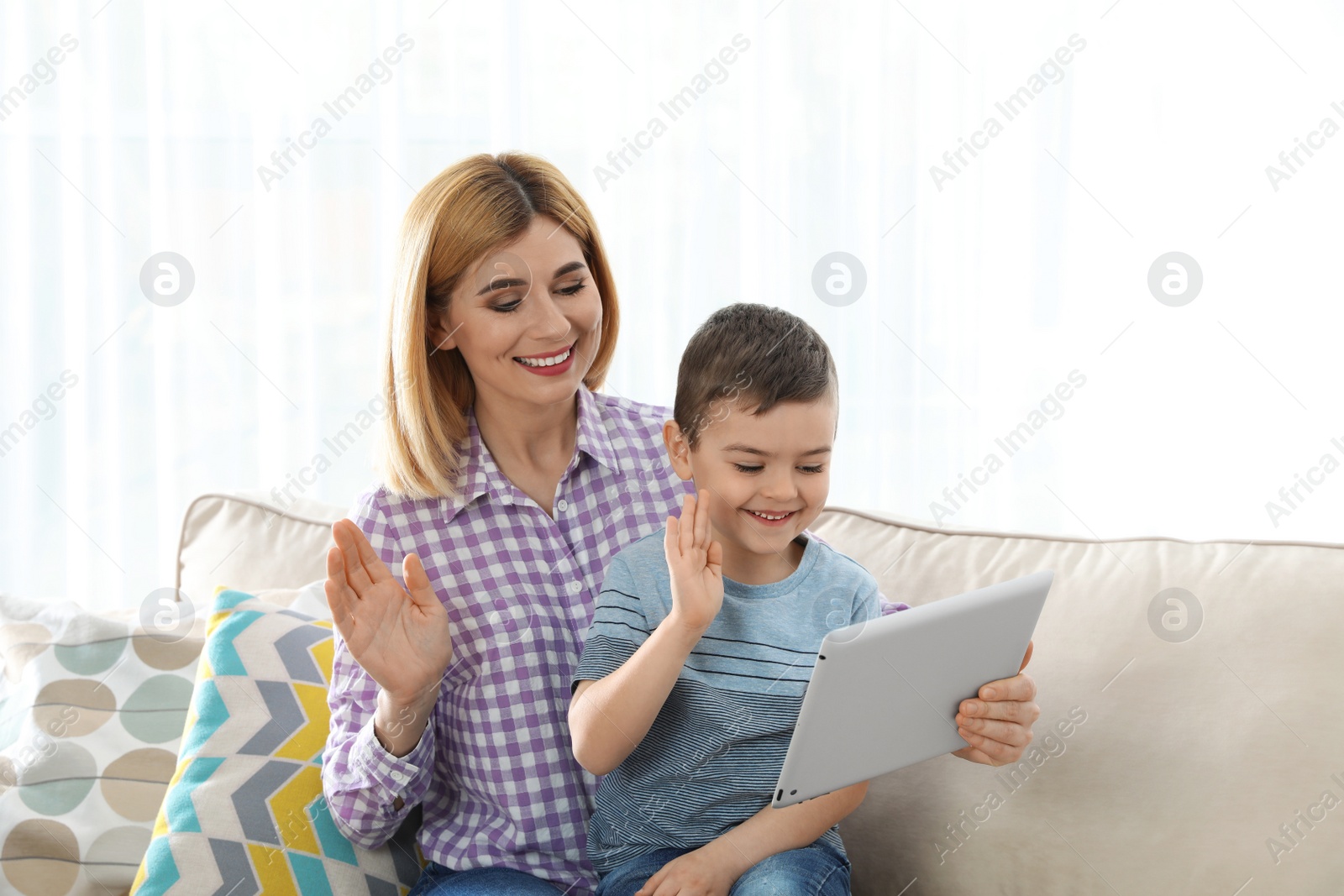 Photo of Mother and her son using video chat on tablet against light background