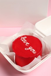 Photo of Tasty bento cake with Love You inscription in takeaway box on pink table