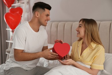 Man presenting gift to his girlfriend at home in morning. Valentine's day celebration