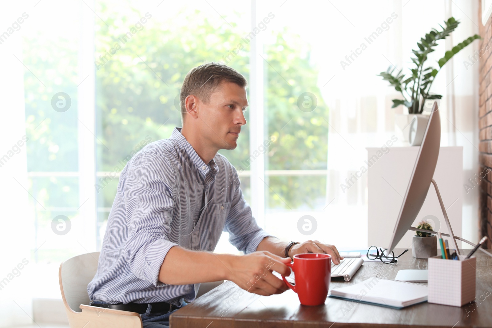 Photo of Young man working with computer in home office