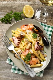 Delicious pasta with sea food served on wooden table, flat lay