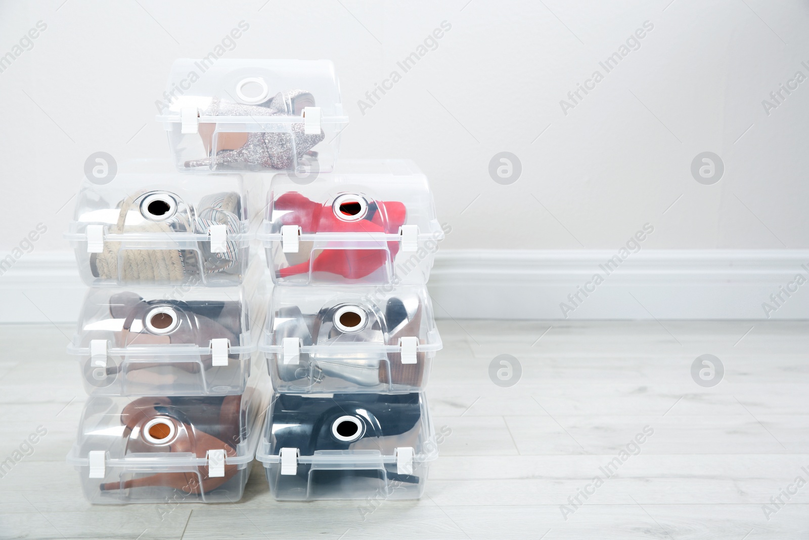 Photo of Shoes in plastic boxes near light wall, space for text. Storage organization