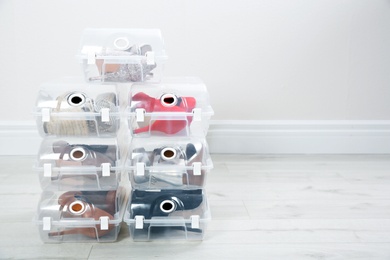 Shoes in plastic boxes near light wall, space for text. Storage organization