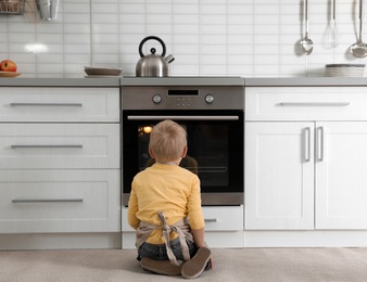 Little boy baking something in oven at home