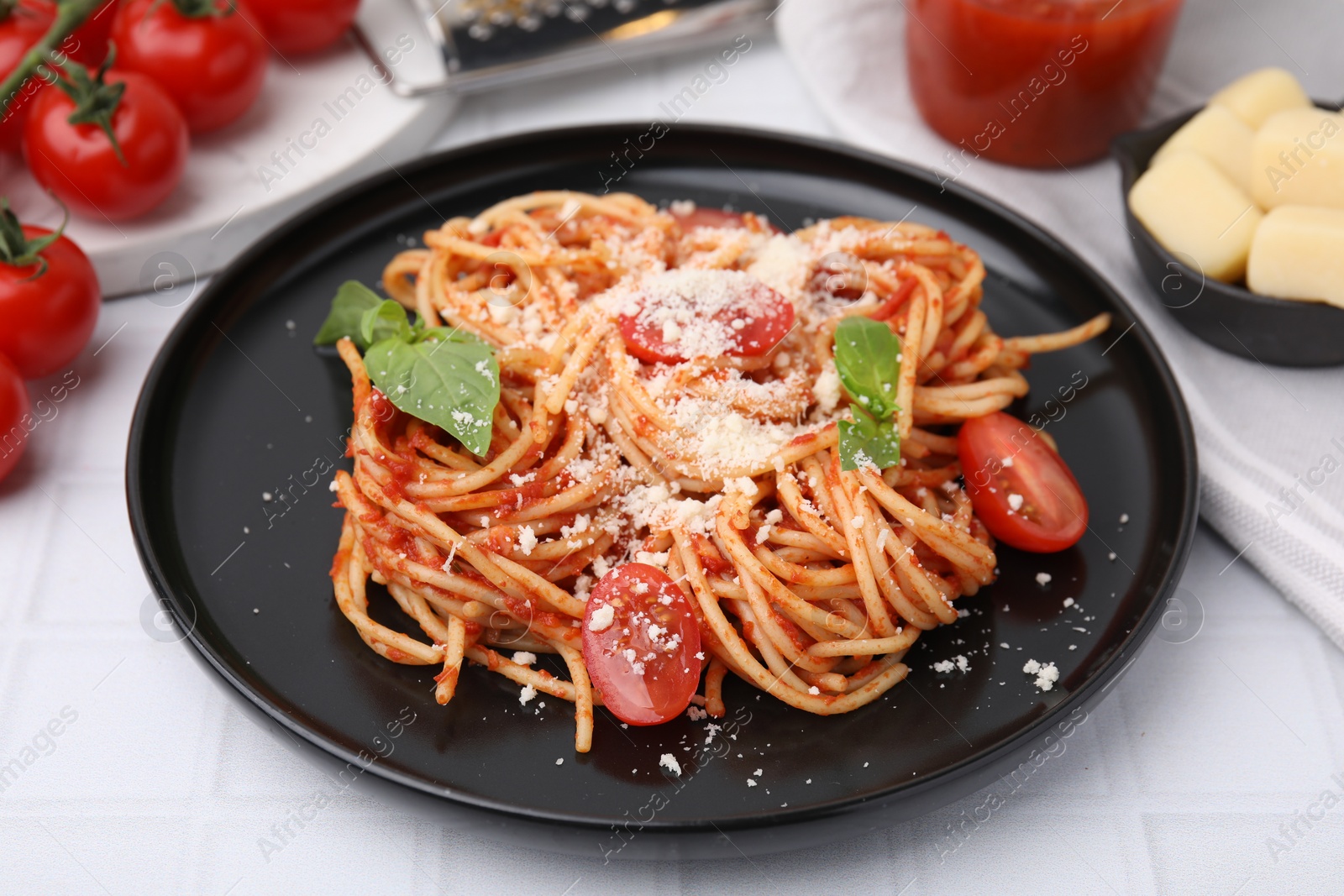 Photo of Tasty pasta with tomato sauce, cheese and basil on white tiled table