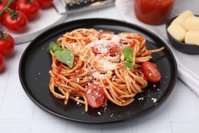 Tasty pasta with tomato sauce, cheese and basil on white tiled table