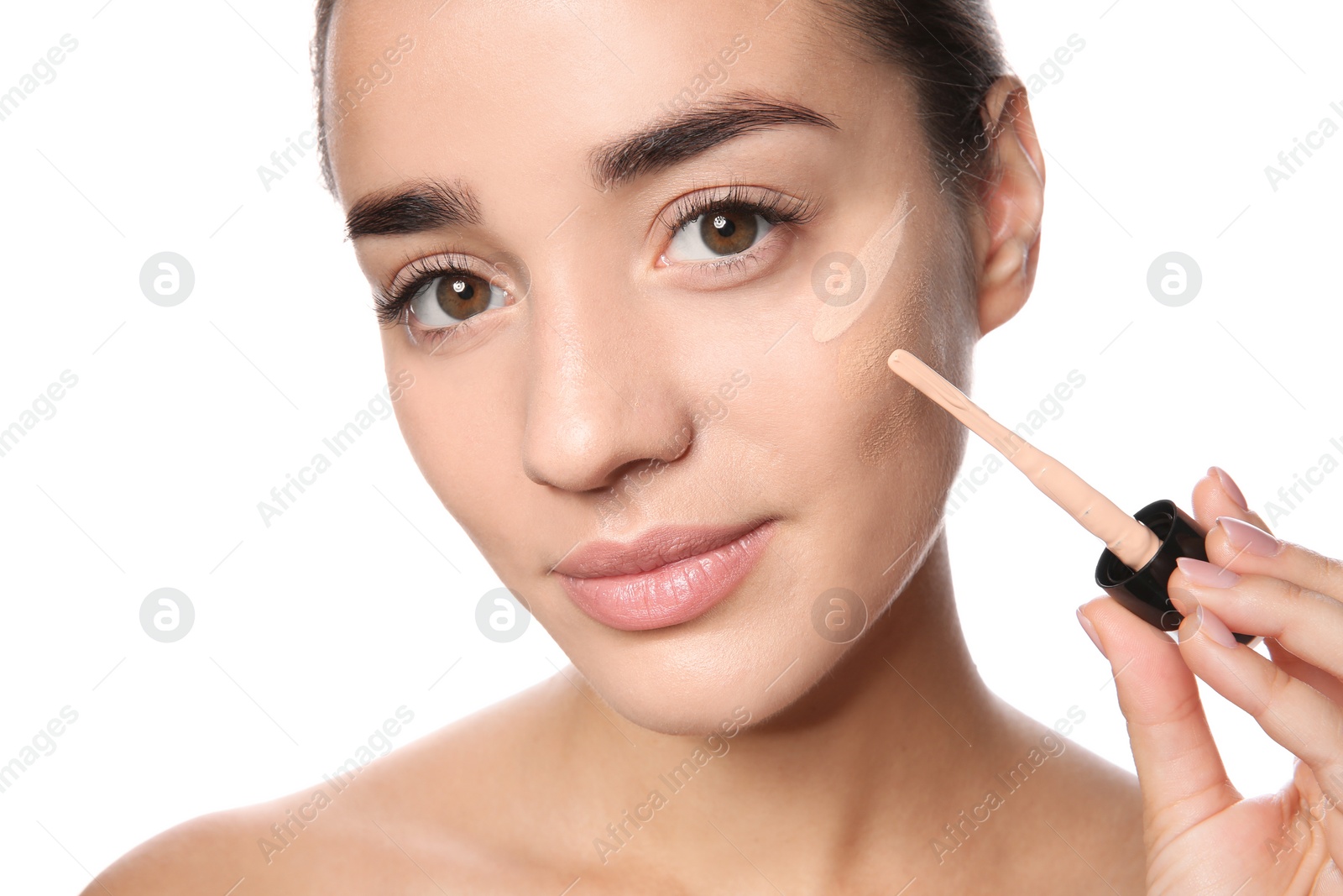 Photo of Young woman applying foundation on her face against white background