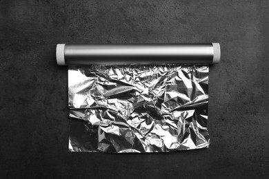 Roll of aluminum foil on dark grey table, top view