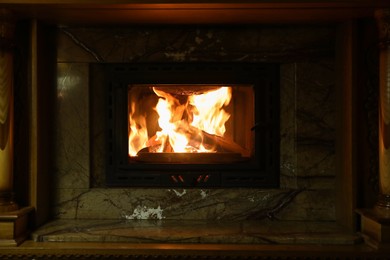 Photo of Fireplace with burning wood in darkness indoors