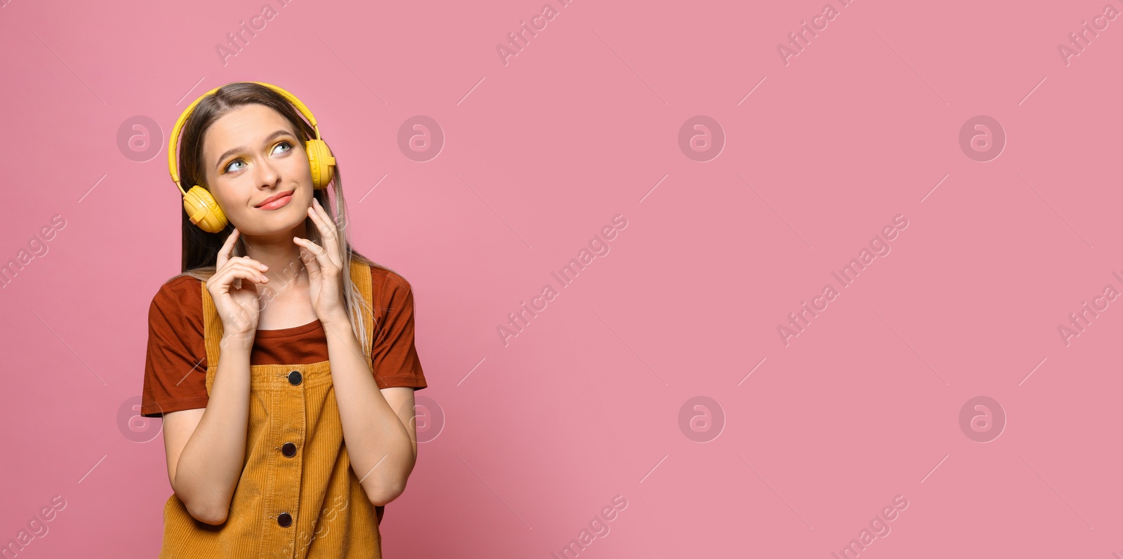 Image of Young woman listening to music with headphones on pink background, space for text. Banner design