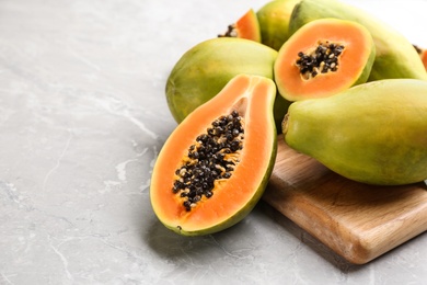 Photo of Fresh ripe papaya fruits on light grey table. Space for text