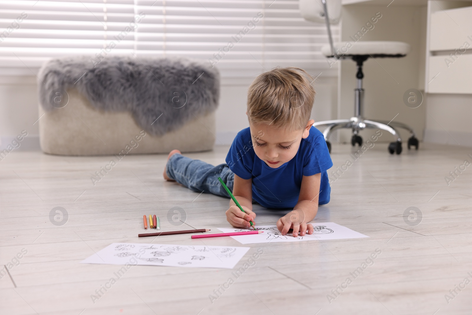 Photo of Cute little boy coloring on warm floor at home. Heating system