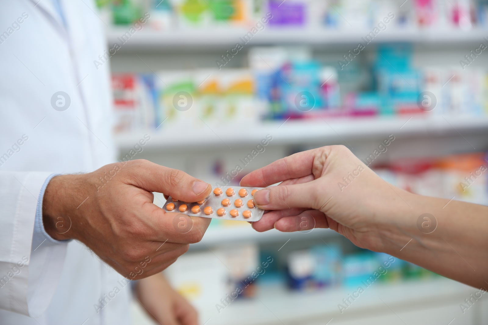 Photo of Professional pharmacist giving pills to customer in drugstore, closeup