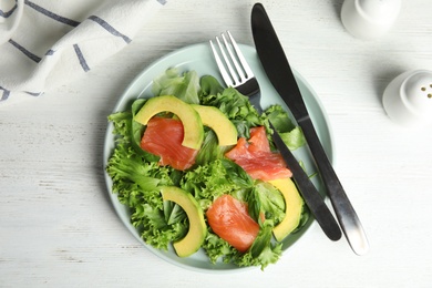 Photo of Delicious avocado salad with salmon on white wooden table, flat lay