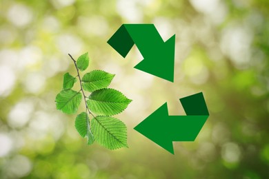Recycling symbol made of arrows and branch with green leaves on blurred background. Bokeh effect