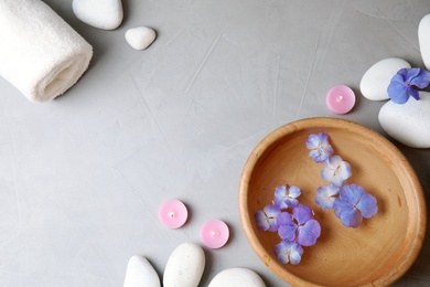 Photo of Flat lay composition with zen stones, spa bowl and towel on grey background. Space for text