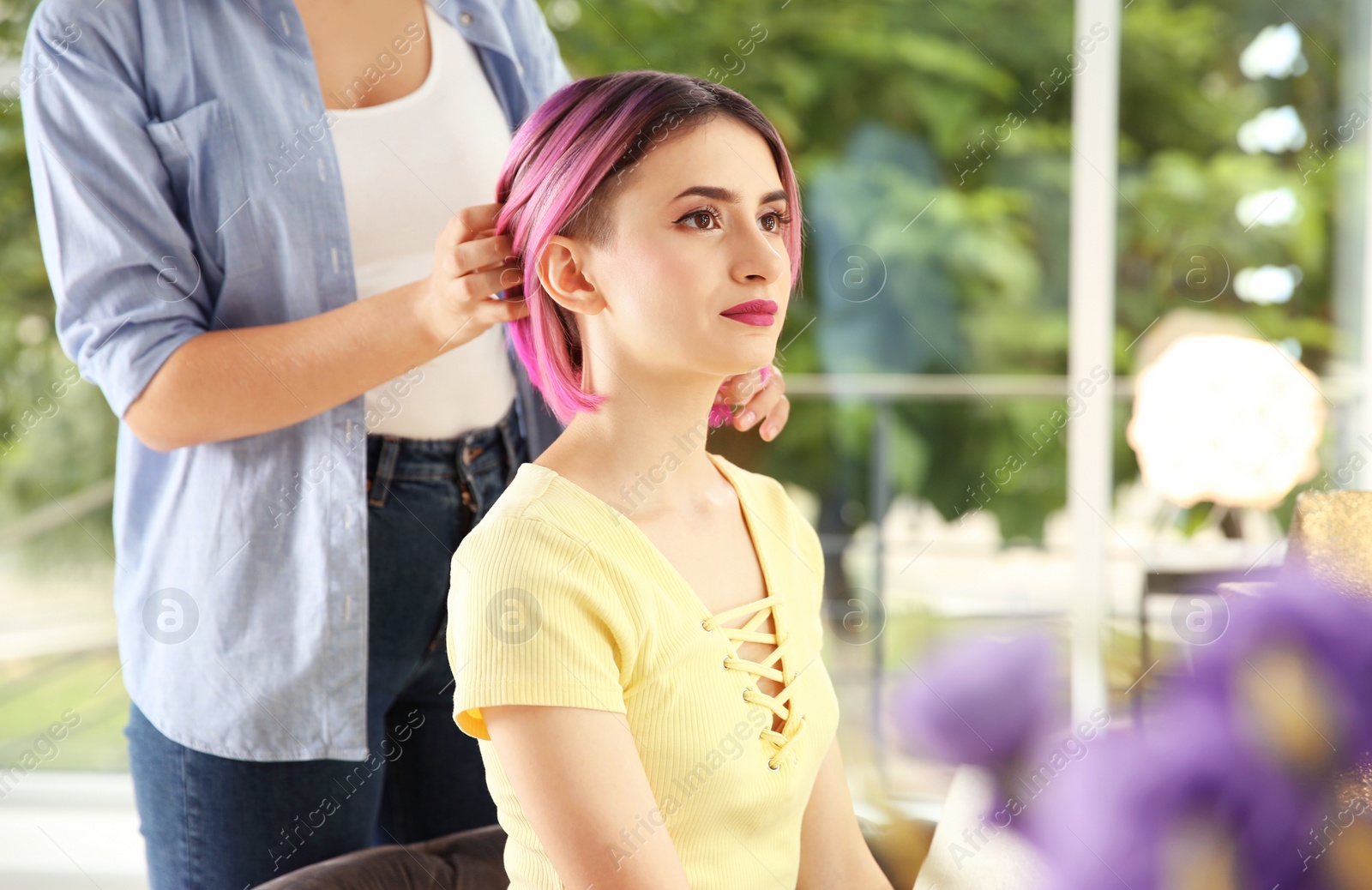 Photo of Professional hairdresser working with young woman in beauty salon. Trendy hair color