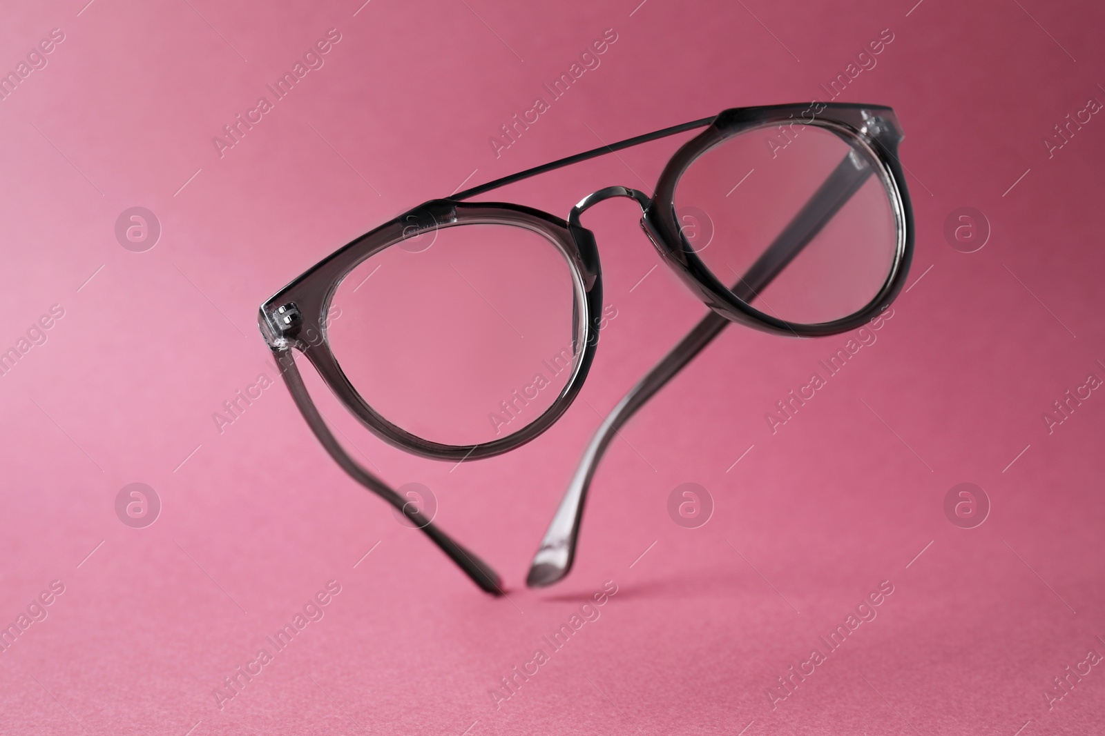 Photo of Stylish pair of glasses with plastic frame on pink background