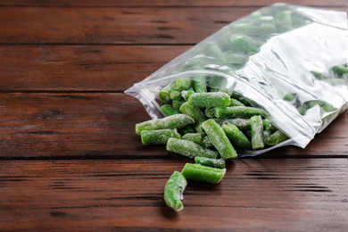 Frozen cut green beans on wooden table. Vegetable preservation