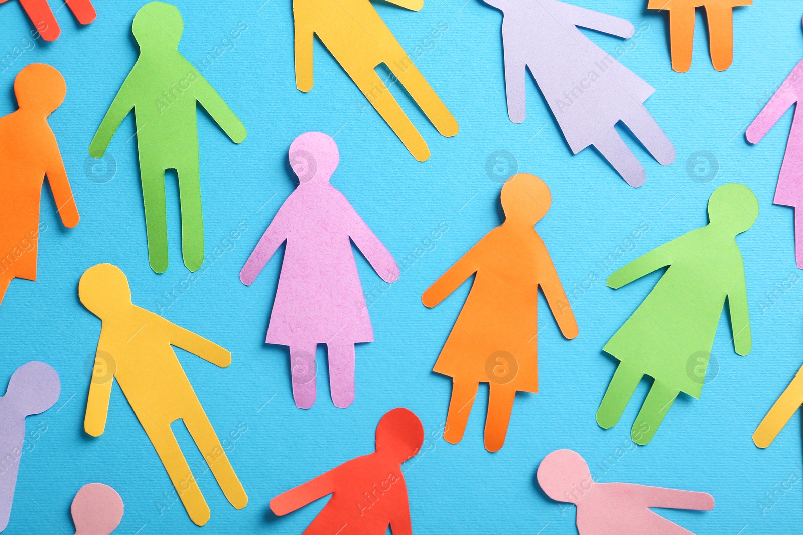 Photo of Many different paper human figures on light blue background, flat lay. Diversity and inclusion concept