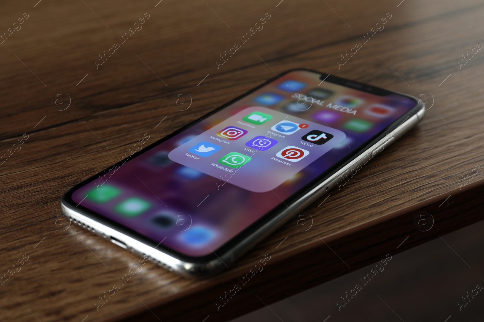 Photo of MYKOLAIV, UKRAINE - AUGUST 10, 2021: Apple iPhone X on wooden table. Screen with different social media icons