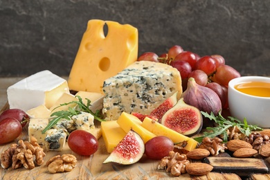 Photo of Set of different snacks with ripe figs served on wooden board