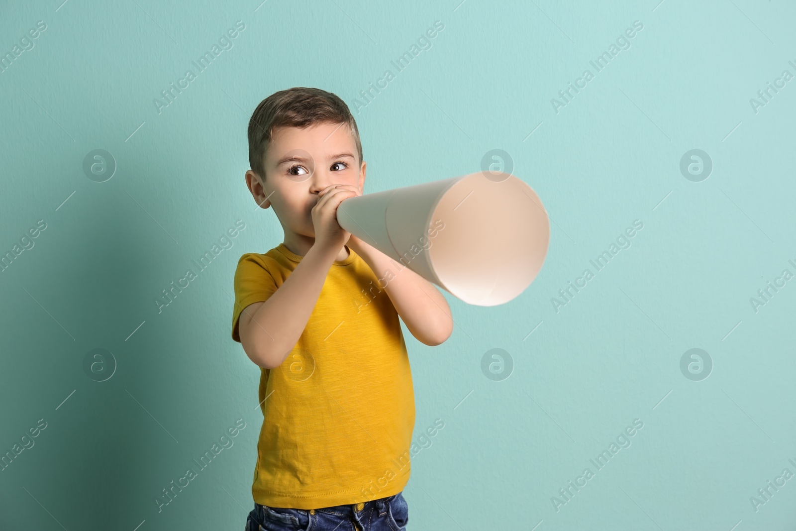 Photo of Adorable little boy with paper megaphone on color background