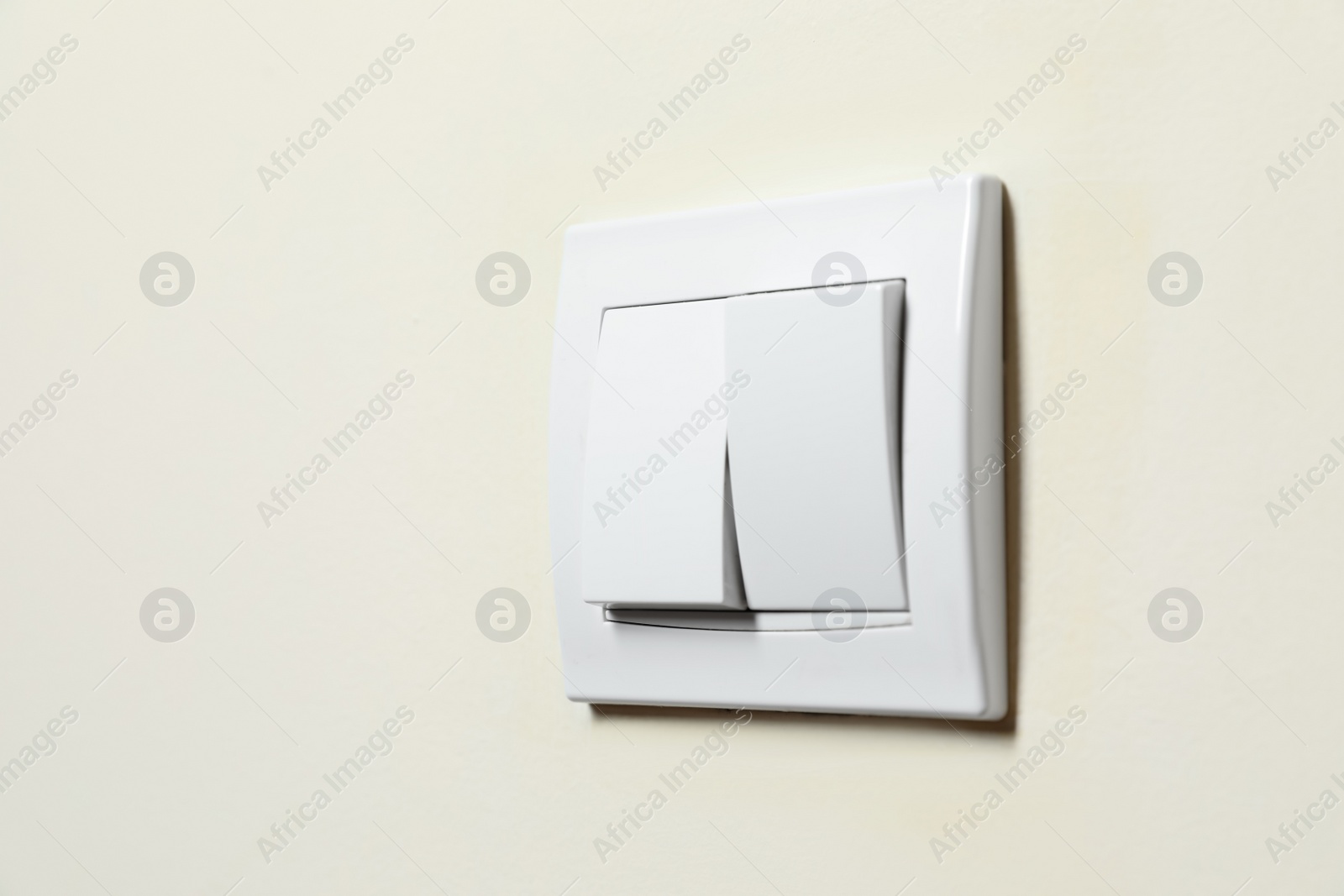 Photo of Modern plastic light switch on white wall, closeup. Space for text