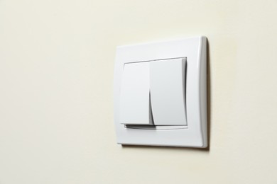 Photo of Modern plastic light switch on white wall, closeup. Space for text