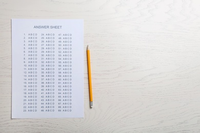 Photo of Answer sheet and pencil on wooden background, top view with space for text