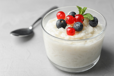 Photo of Delicious rice pudding with berries on light table, closeup. Space for text