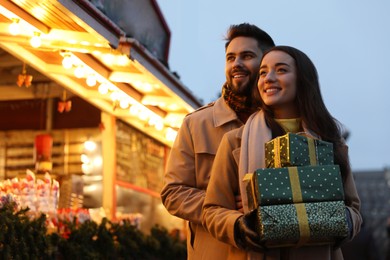 Photo of Lovely couple with Christmas presents at winter fair